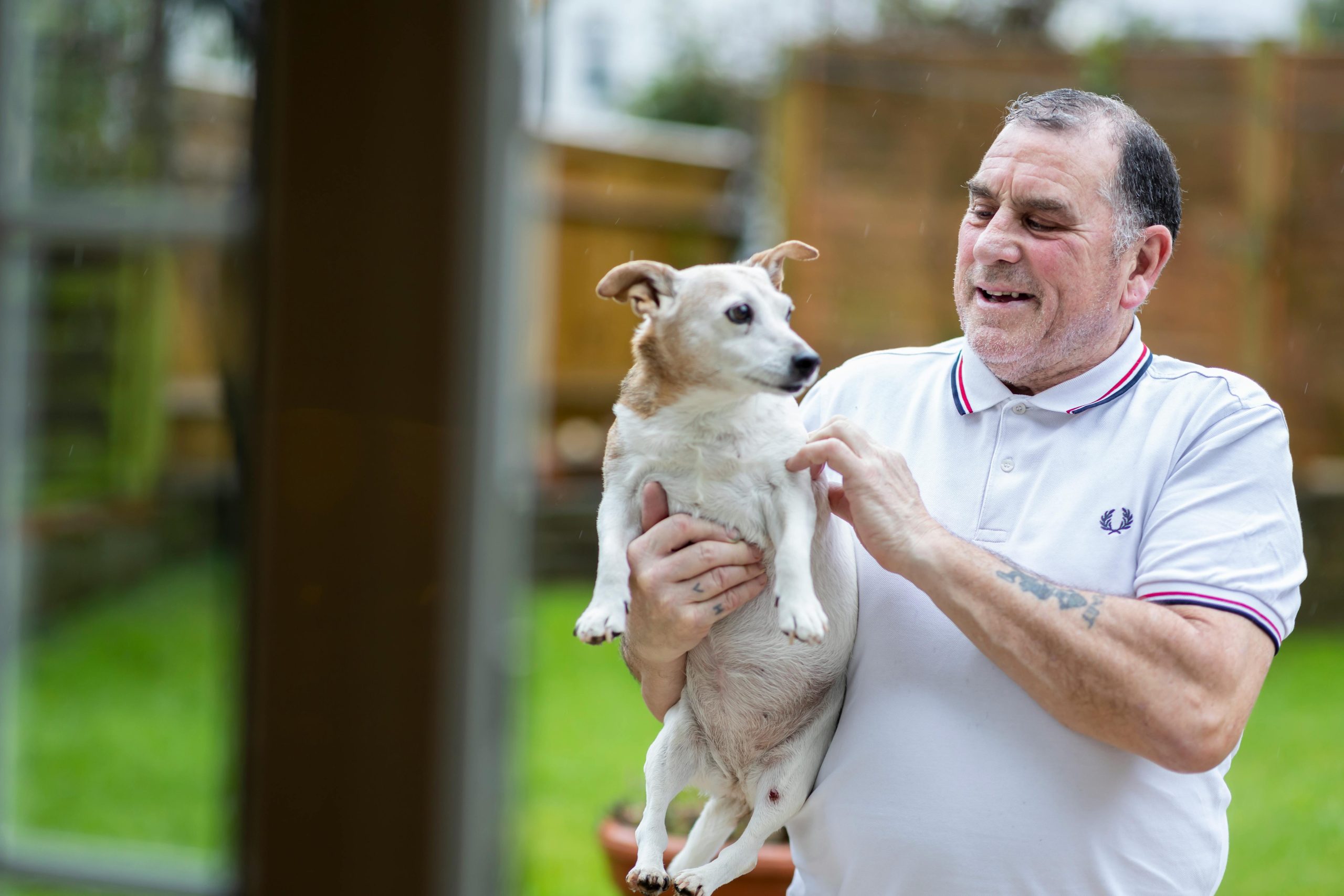 Elderly Man in Polo Shirt Holding Senior Pet in Hands // Healthier Pets Today