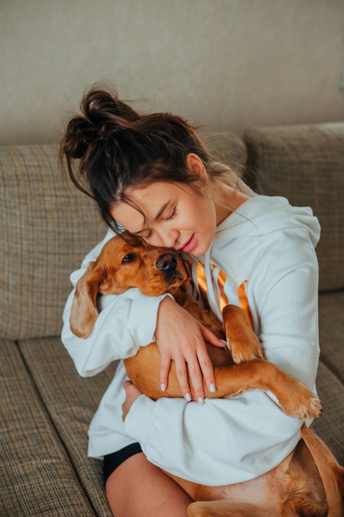 Tender woman hugging obedient dog at home // Healthier Pets Today