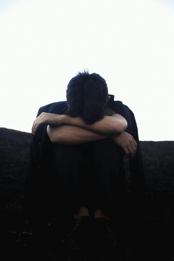 Unrecognizable upset man sitting on ground and embracing knees // Healthier Pets Today
