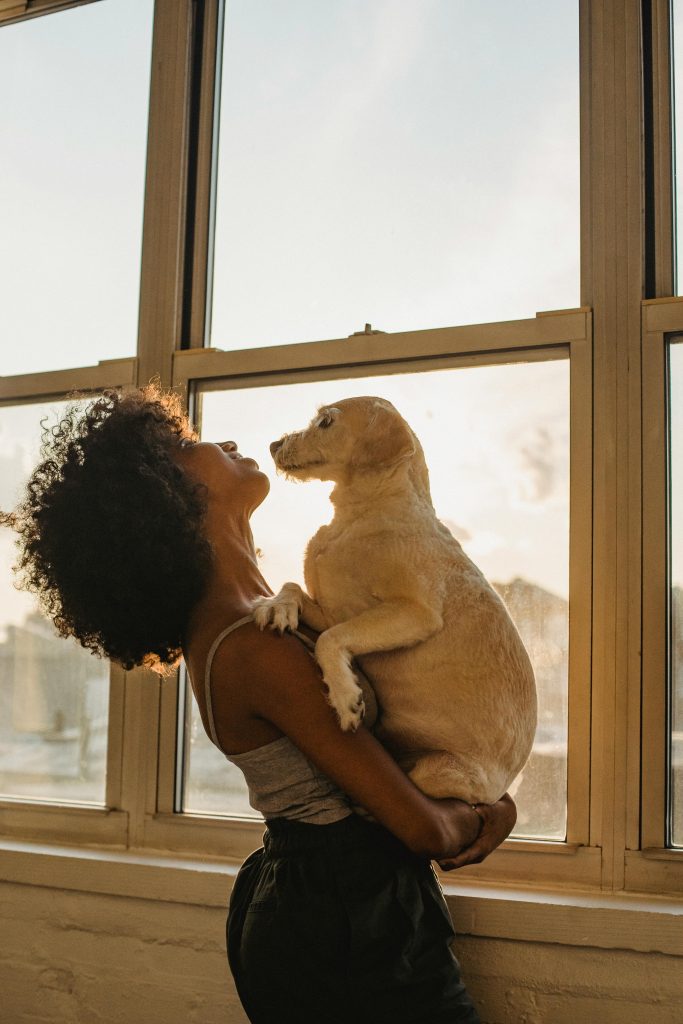 Black woman with dog near window // Healthier Pets Today