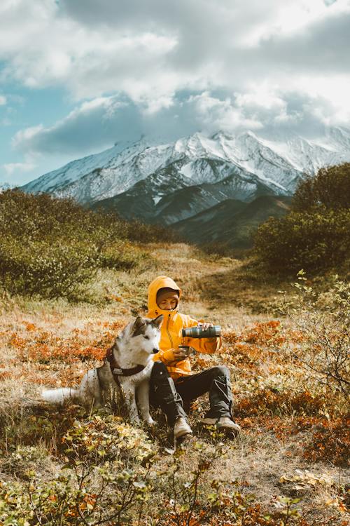 Tired traveler with Husky on mountainous terrain // Healthier Pets Today