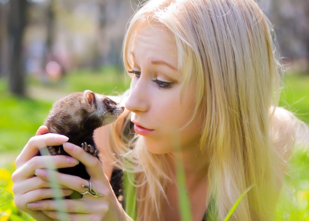 Woman playing with a ferret on the grass // Healthier Pets Today
